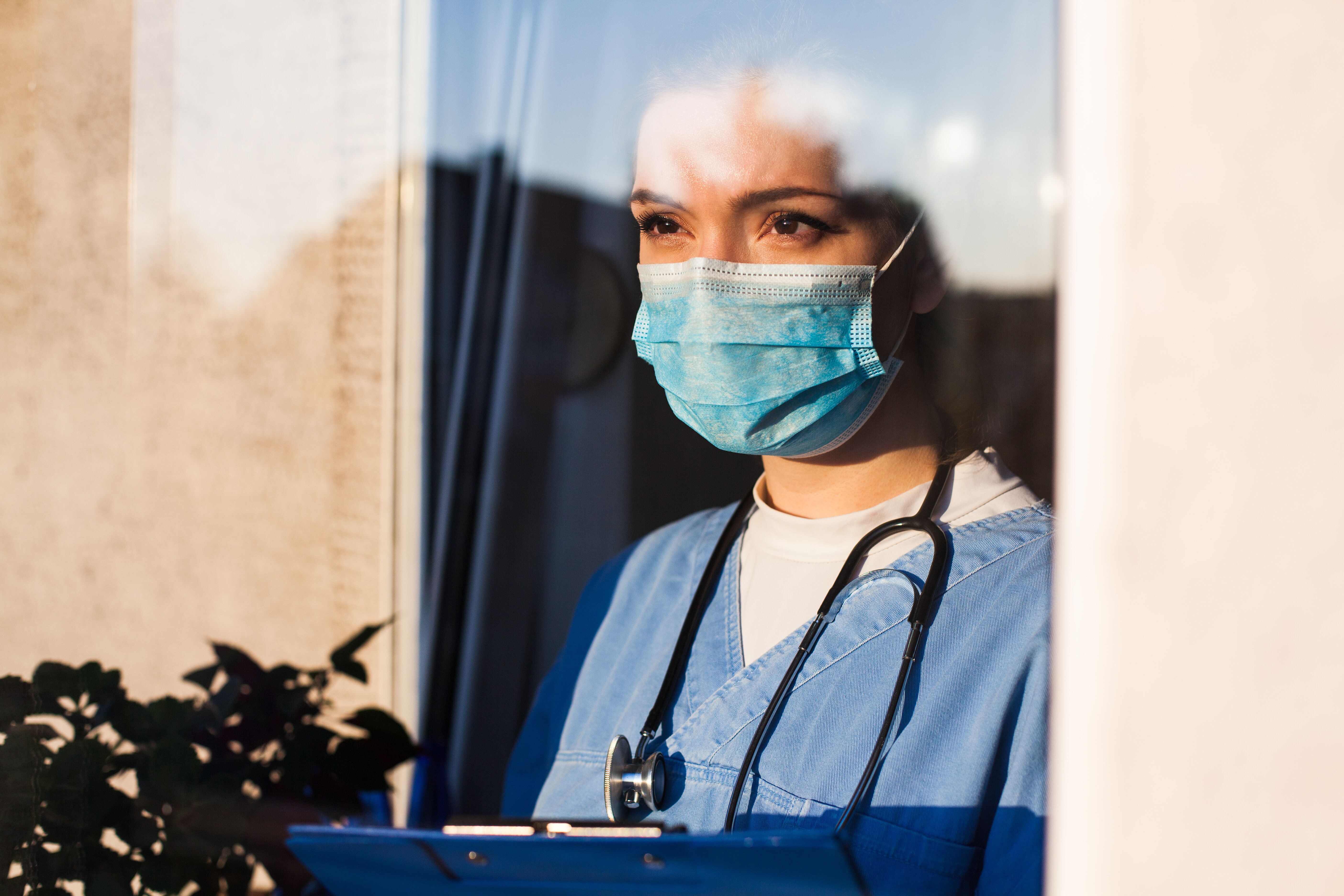 Nurse wearing face mask looking through window
